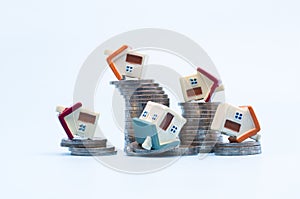 Mini house on stack of coins on  white background,  Concept of Investment property, Investment risk and uncertainty in the real
