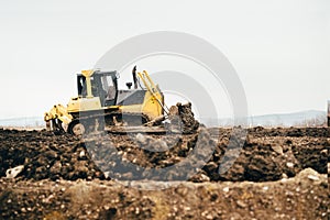 Mini industrial bulldozer moving dirt and earth with scoop. Industrial details of landscaping