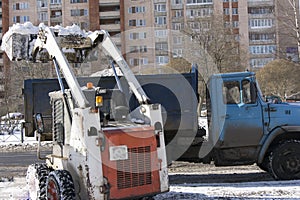 The mini-loader removes snow, clearing the city .Cleaning of the territory by public utilities in winter