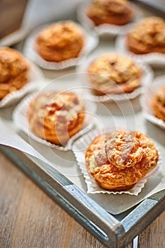 Mini meat pies from flaky dough on a tray over wooden background.