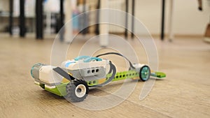 Mini model of plastic electronic car moves dow the floor close up view slow motion