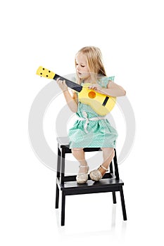 Mini muso. Studio shot of a cute little girl playing with her toy guitar against a white background. photo