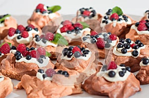 Mini Pavlova meringue nests with berries and mint on on white background