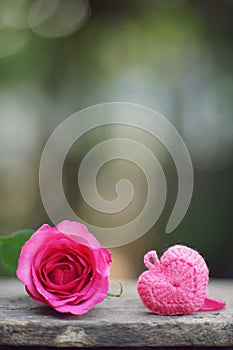 Mini pinky heart and single elegant pink color rose flower decorated with petals on wood table background, sweet valentine present