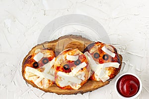 Mini pizza as mummy for kids with cheese, olives and ketchup. Funny crazy Halloween food for children