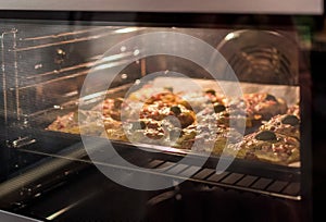 Mini pizzas baking in electric oven in kitchen.