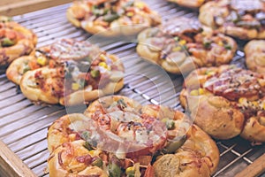 Mini pizzas with cheese, tomato, green beans, corn and sausages in the shoppin mall, small italian bakery. Tropical