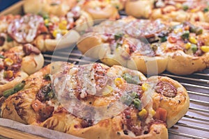 Mini pizzas with cheese, tomato, green beans, corn and sausages in the shoppin mall, small italian bakery. Tropical