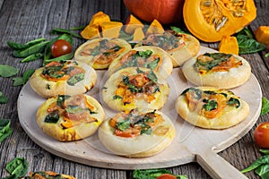 Mini pizzas with pumpkin, spinach and tomatoes on a pizza shovel