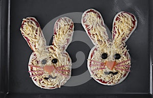 Mini pizzas in the shape of a rabbit before baking on baking sheet, preparatory stage