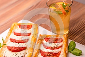 mini pizzas with tomatoes and mozzarella. and homemade lemonade on a wooden table. Side, close-up