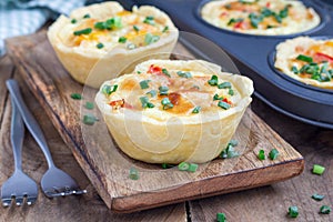 Mini quiche with chicken and bell pepper on a wooden plate