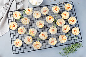 Mini quiche muffins with feta cheese, fried onion, thyme and red bell pepper, on cooling rack, horizontal, top view