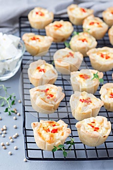 Mini quiche muffins with feta cheese, fried onion, thyme and red bell pepper, on cooling rack,  vertical