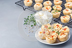 Mini quiche muffins with feta cheese, fried onion, thyme and red bell pepper, on white plate and cooling rack, horizontal, copy