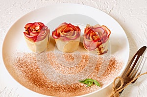 Mini rose tarts with apples and mint leaves on the white plate