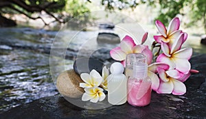 Mini set of bubble bath shower gel liquid with flowers and pebble on waterfall rock