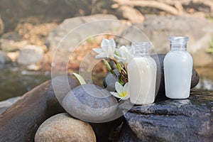 Mini set of bubble bath shower gel liquid with flowers and pebble on waterfall rock