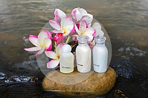 Mini set of bubble bath shower gel liquid with flowers and pebble on waterfall rock