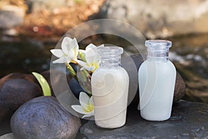 Mini set of bubble bath shower gel liquid with flowers and pebble on waterfall rock