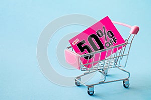 Mini shopping cart with a fifty percent discount sign on blue background.