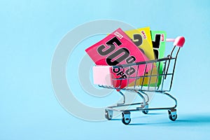 Mini shopping cart with a fifty percent discount sign on blue background.