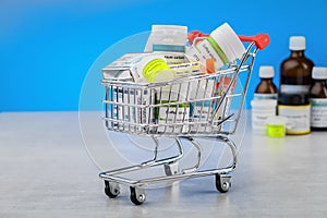 Mini shopping cart full of homeopathic remedies on blue background.