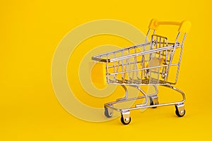 Mini shopping cart isolated on yellow background. Empty supermarket trolley. Buying online concept.