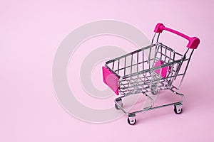 Mini shopping cart retail theme Little shopping cart on a pink paper background
