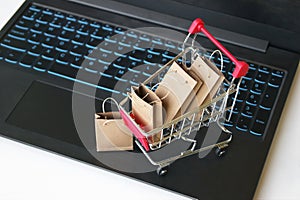 Mini shopping cart with small craft bags on the background of the keyboard