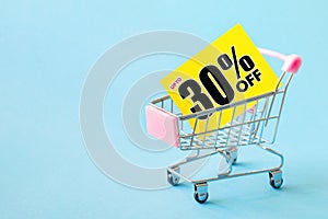 Mini shopping cart with a thirty percent discount sign.