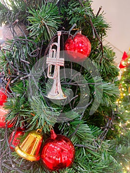 A mini silver trumpet, a small golden bell, red balls and a light bulb line decorate the Christmas tree .