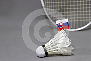 Mini Slovakia flag stick on the white shuttlecock on the grey background and out focus badminton racket