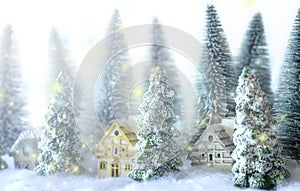 Mini snowy Christmas trees with houses in the forest. Bokeh lights background