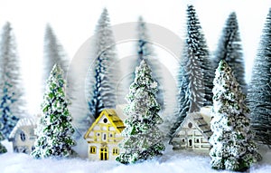 Mini snowy Christmas trees with houses in the forest. Bokeh lights background