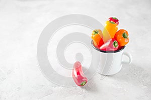 Mini sweet clorful pepeers in a cup over grey background