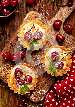 Mini Tarts with fresh cherries and vanilla custard and caramel, delicious dessert on a wooden table