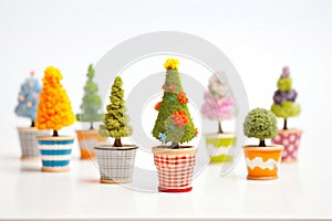 mini topiaries in colorful pots on a white surface