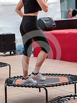 Mini trampoline workout: girl doing fitness exercise in class at gym