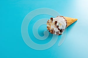 Mini Vanilla flavor ice cream cone starts melting on blue