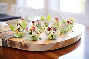 mini waldorf salads in bite-sized lettuce cups on a wood tray