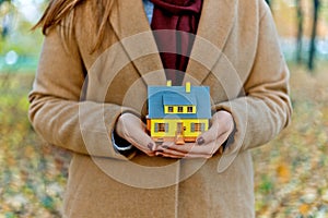 Mini yellow house model in woman hands for mortgage offers and money saving with the buying a property or interior design