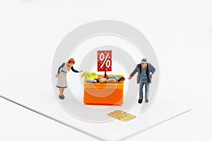 Miniatrue people: Shoppers buy goods on sale with discount tray