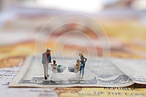 Miniatrue people: Shoppers with shopping cart standing on the  money. and world map. Shopping  and business concept