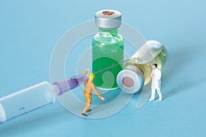 A miniatue worker carrying a syringe to a doctor