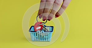 Miniature basket with house keys on yellow background