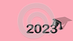 Miniature black graduated cap and numbers 2023 on pink background. Class of 2023 concept