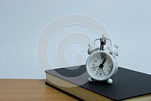 Miniature business concept - a man standing above clock and notebook. workload concept