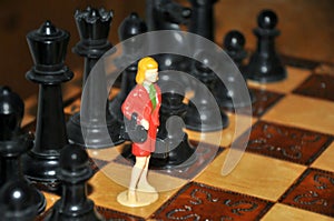 Miniature business woman between chess pieces pawns figures on chessboard. Competition, gender, individuality concept