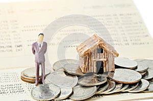 Miniature businessman stand on the heap coins on book bank background.